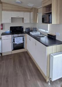 eine Küche mit weißen Schränken und einer schwarzen Arbeitsplatte in der Unterkunft Homely 8 Berth Caravan At Harts Holiday Park In Kent Ref 74069B in Leysdown-on-Sea