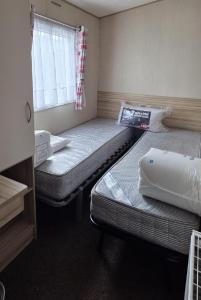 zwei Betten in einem kleinen Zimmer mit Fenster in der Unterkunft Homely 8 Berth Caravan At Harts Holiday Park In Kent Ref 74069B in Leysdown-on-Sea