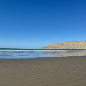 a beach with the ocean and a blue sky at Sol del Atardecer in Rada Tilly
