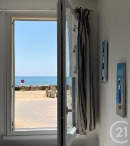 an open door with a view of the beach at Waterfront apartment - Plage des Mouettes in Saint-Hilaire-de-Riez