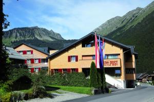 een hotel met een vlag voor een gebouw bij Alpen Hotel Post in Au im Bregenzerwald