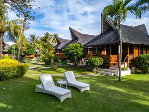 une maison avec deux chaises blanches devant dans l'établissement Pura Vida Beach & Dive Resort, à Dauin