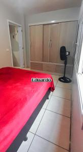 ein Schlafzimmer mit einer roten Bettdecke auf einem Bett in der Unterkunft Apartamento pé na areia no centro de Tramandaí! in Tramandaí