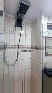 ein Bad mit einer Dusche und einem Laptop an der Wand in der Unterkunft Apartamento pé na areia no centro de Tramandaí! in Tramandaí