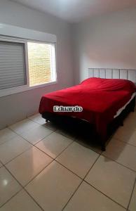 ein Schlafzimmer mit einem Bett mit einer roten Decke darauf in der Unterkunft Apartamento pé na areia no centro de Tramandaí! in Tramandaí + 5 Fotos