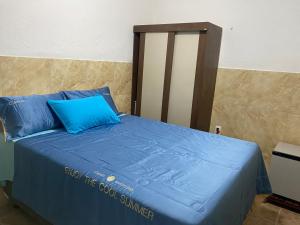 uma cama com almofadas azuis e um cartaz em Blue Sapphire guest house em Caucaia
