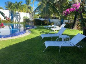 um grupo de cadeiras sentadas na grama perto de uma piscina em Blue Sapphire guest house em Caucaia