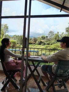 un homme et une femme assis à une table regardant un champ dans l'établissement Habitación Orquídea - Hospedaje Rural La Fortaleza, à San Miguel 1 autre photo