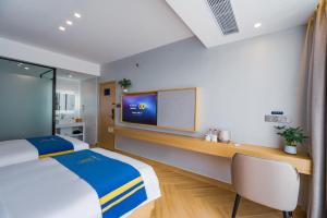 a hotel room with a bed and a flat screen tv at Super 8 Selected Hotel Sanya Bay Coconut Dream Corridor in Sanya