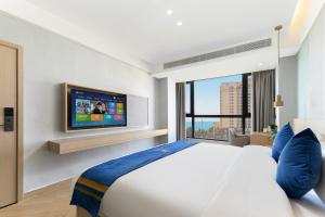 a bedroom with a large bed and a tv at Super 8 Selected Hotel Sanya Bay Coconut Dream Corridor in Sanya