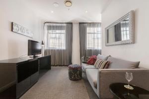 a living room with a couch and a tv at Punthill Apartment Hotel - Flinders Lane in Melbourne