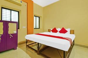 um quarto com uma cama com travesseiros vermelhos e uma porta roxa em Hotel O Golden Key em Nagpur