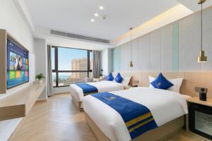 two beds in a hotel room with a tv at Super 8 Selected Hotel Sanya Bay Coconut Dream Corridor in Sanya +13 photos