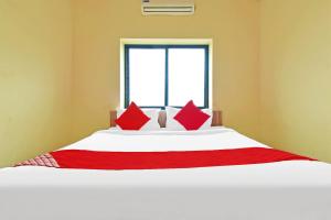 um quarto com uma grande cama branca com travesseiros vermelhos em Hotel O Golden Key em Nagpur