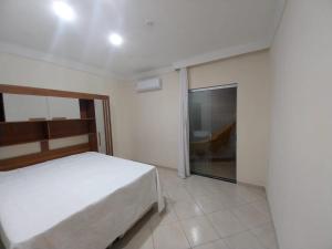 Un dormitorio con una cama y una puerta corrediza de vidrio. en Apartamento próximo avenida São Domingos, en Feira de Santana