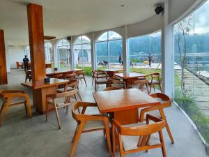 a restaurant with wooden tables and chairs and windows at Lushy Hostel Kintamani in Kubupenlokan