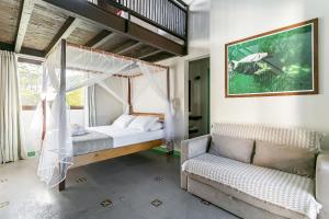 a bedroom with a canopy bed and a couch at Pousada Rosa 08 - Café da manhã Gourmet, Suítes com Banheira a 150m do Centrinho da Praia do Rosa in Praia do Rosa +140 photos