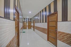 pasillo con puertas de madera y pared de ladrillo en Hotel O Vrishti Hotels by Ananda, en Sūrajpur