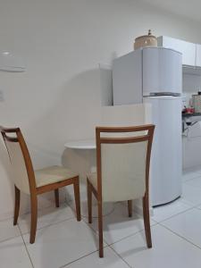 a kitchen with two chairs and a white refrigerator at Apê econômico a 10 km de Porto in Ipojuca +6 photos