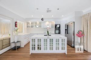 una cocina con armarios blancos y una isla blanca en Luxury Waterfront Getaway, en Toukley