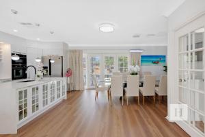 Una cocina y un comedor con mesa y sillas. en Luxury Waterfront Getaway, en Toukley