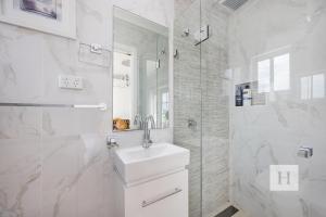 Un baño blanco con lavabo y ducha. en Luxury Waterfront Getaway, en Toukley 22 fotos más