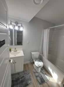 a white bathroom with a toilet and a sink at Comfortable Two Bed Basement With Free WiFi, Laundry and Private Entry in Regina +13 photos