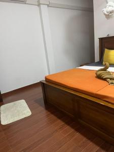 a bedroom with a bed with orange sheets and a rug at The Ceylan Crest Hotel Ella in Ella +2 photos