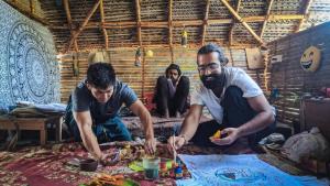 een groep van drie mannen die in een kamer eten bij Time Travellers in Auroville
