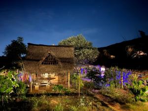een huis met rieten dak in een tuin 's nachts bij Time Travellers in Auroville