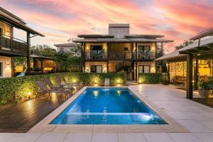 a house with a swimming pool in front of a house at Pousada Rosa 08 - Café da manhã Gourmet, Suítes com Banheira a 150m do Centrinho da Praia do Rosa in Praia do Rosa