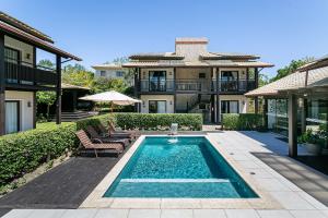 a house with a swimming pool in front of a house at Pousada Rosa 08 - Café da manhã Gourmet, Suítes com Banheira a 150m do Centrinho da Praia do Rosa in Praia do Rosa