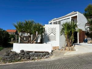a white house with palm trees in front of it at Hummocks in Sesoko