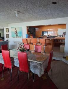 a dining room with a table and red chairs at Casa Vacacional Chula Vista in Acapulco