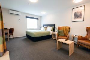 a hotel room with a bed and a table and chairs at Tussock Peak Lodge in Hanmer Springs