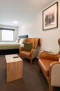 a living room with a bed and a couch and chairs at Tussock Peak Lodge in Hanmer Springs +126 photos