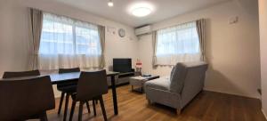 een woonkamer met een tafel, stoelen en een televisie bij KamakurakoshigoeekimaeA in Kamakura