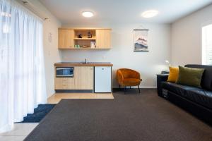 a living room with a couch and a kitchen at Tussock Peak Lodge in Hanmer Springs