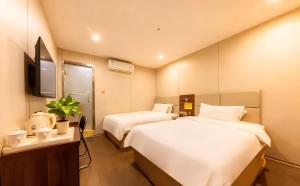 a hotel room with two beds and a tv at Baiyuan Hotel Changgang Baogang Avenue Metro Station Branch in Guangzhou