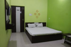 a bedroom with a bed in a room with green walls at OYO 86877 Hotel Bhuneshwar Inn in Rāmgarh