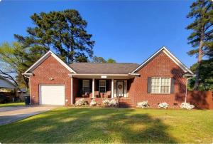 a red brick house with a white garage at Charming Comfy Retreat - Crib, Pet-Friendly, 7 miles to Ft Bragg, Veteran-Owned in Fayetteville