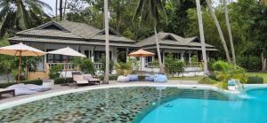 a villa with a swimming pool in front of a house at Marilyn’s Resort Koh Samui in Lamai