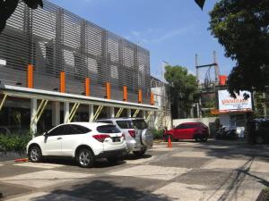 two cars parked in a parking lot in front of a building at Gandasari Hotel in Bandung