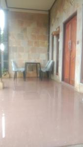 a patio with two chairs and a table and a door at Dewenten Backpacker II in Tulamben