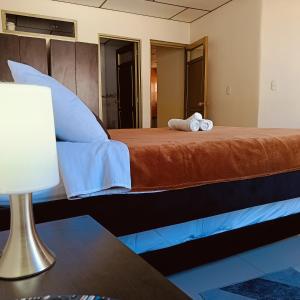 RuiosucioにあるApartaestudio central con balcón y wifi en Riosucioのランプとテーブルが備わる部屋のベッド1台分です。