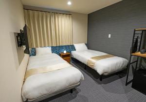 a hotel room with two beds and a television at Stay SAKURA Kyoto Station Shichijo in Kyoto
