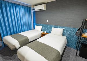 two beds in a hotel room with blue curtains at Stay SAKURA Kyoto Station Shichijo in Kyoto