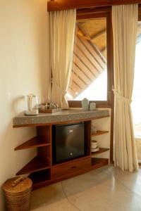 a living room with a tv and a window at Kini Resort - Oceanfront Bamboo Eco Lodges in Sekongkang +56 photos