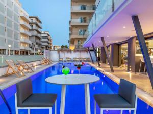 a pool with a table and chairs and a drink on it at Mercure Rhodes Alexia Hotel & Spa in Rhodes Town