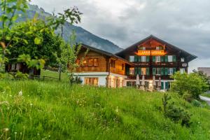 ein Haus in den Bergen mit grünem Feld in der Unterkunft Cortesi's Lenk Lodge, Boutiques Appartements in Lenk im Simmental